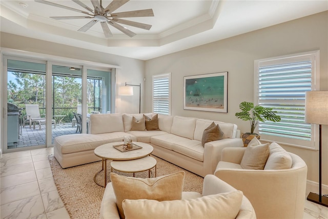 living room featuring ceiling fan, ornamental molding, and a tray ceiling