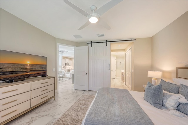 bedroom featuring a barn door, ensuite bath, and ceiling fan