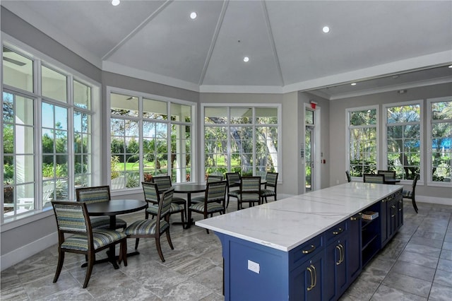 interior space featuring light stone countertops, blue cabinets, vaulted ceiling, and plenty of natural light