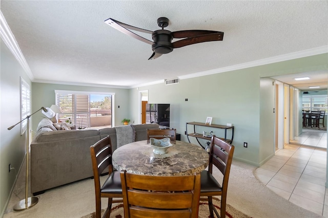 tiled dining space with ceiling fan, ornamental molding, and a textured ceiling