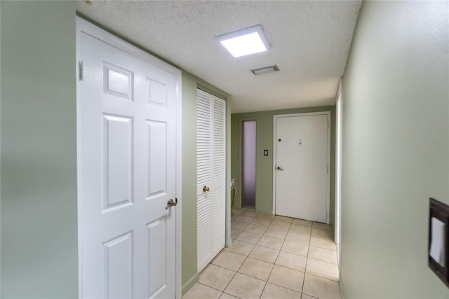 hall featuring light tile patterned floors and a textured ceiling