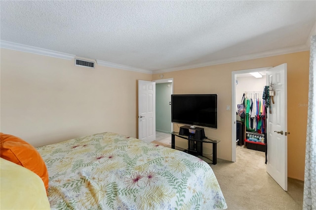 bedroom with a walk in closet, ornamental molding, a textured ceiling, light colored carpet, and a closet