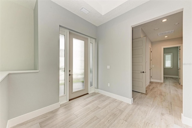 foyer featuring plenty of natural light, a textured ceiling, and light wood-type flooring