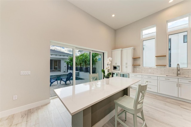 kitchen with stainless steel microwave, white cabinets, sink, and a kitchen island