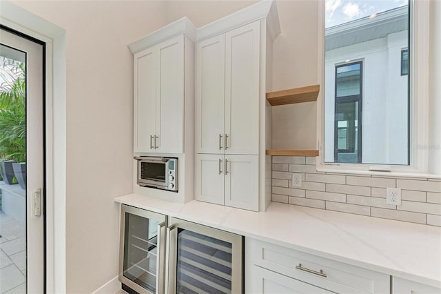 bar featuring white cabinets, decorative backsplash, wine cooler, and light stone counters