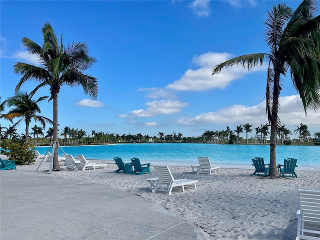 view of pool with a water view and a beach view