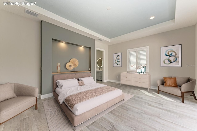 bedroom featuring light wood-type flooring and a tray ceiling