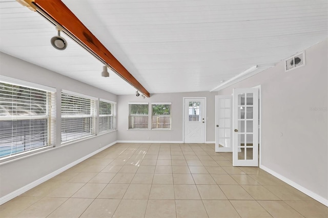 unfurnished sunroom with beamed ceiling and french doors