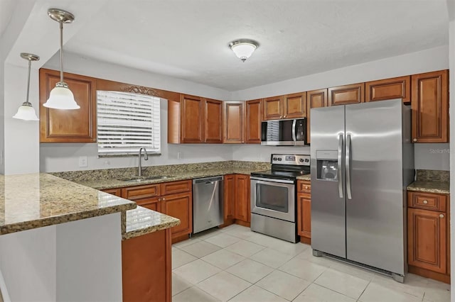 kitchen featuring sink, hanging light fixtures, light stone counters, kitchen peninsula, and appliances with stainless steel finishes