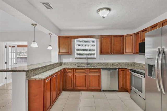 kitchen with light stone countertops, sink, kitchen peninsula, pendant lighting, and appliances with stainless steel finishes