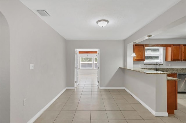 kitchen with light stone countertops, stainless steel dishwasher, kitchen peninsula, decorative light fixtures, and light tile patterned floors