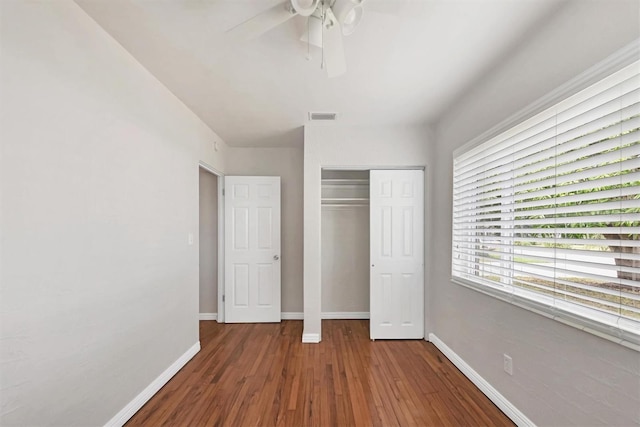 unfurnished bedroom with dark hardwood / wood-style flooring, a closet, and ceiling fan