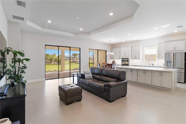 tiled living room with a raised ceiling and sink