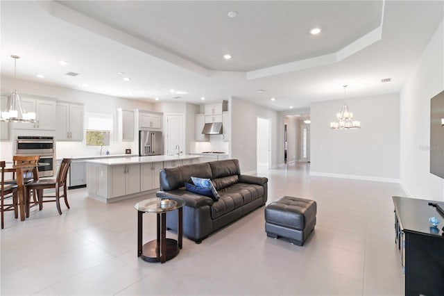 living room featuring light tile patterned floors, a tray ceiling, and sink