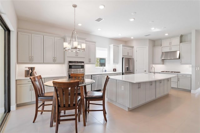 kitchen with sink, an island with sink, a chandelier, pendant lighting, and appliances with stainless steel finishes