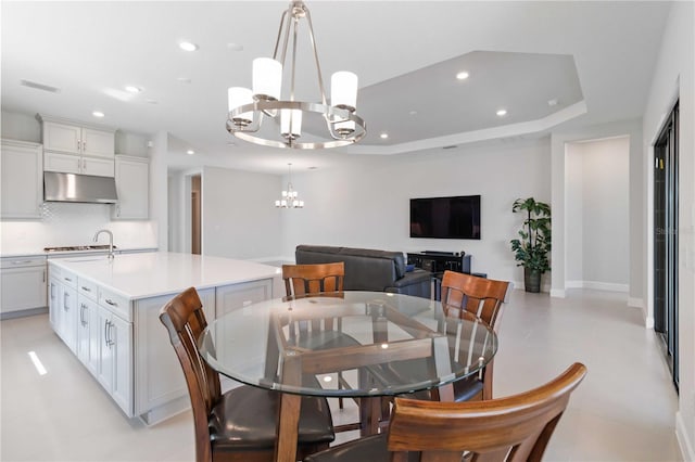 dining space with a raised ceiling, light tile patterned floors, and a notable chandelier