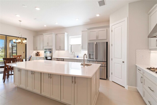 kitchen with sink, stainless steel appliances, plenty of natural light, and an island with sink