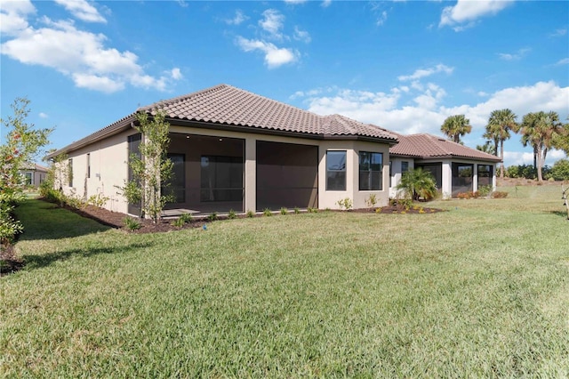 rear view of property with a lawn and a sunroom