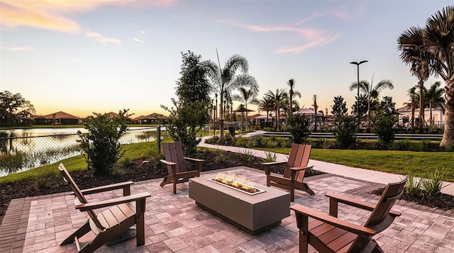 patio terrace at dusk featuring a water view and a fire pit