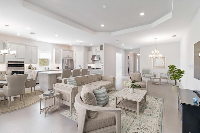 tiled living room featuring a notable chandelier and a raised ceiling