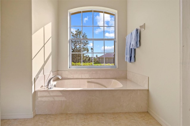 bathroom with tiled tub, plenty of natural light, and tile patterned flooring