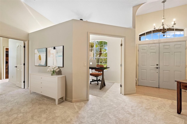 carpeted foyer entrance featuring high vaulted ceiling and an inviting chandelier