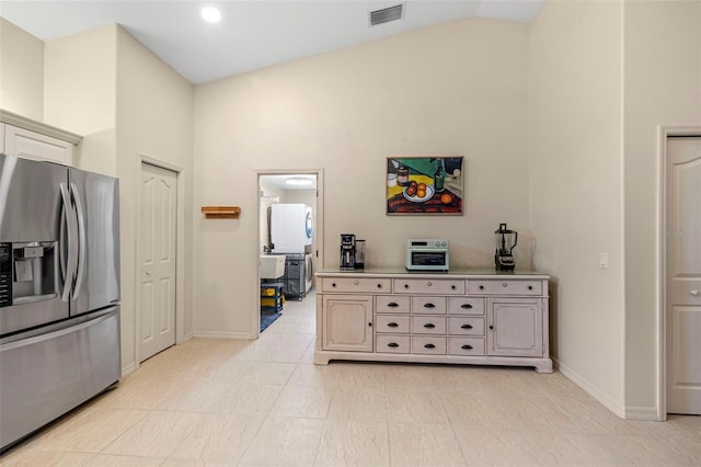 kitchen with stainless steel refrigerator with ice dispenser and high vaulted ceiling