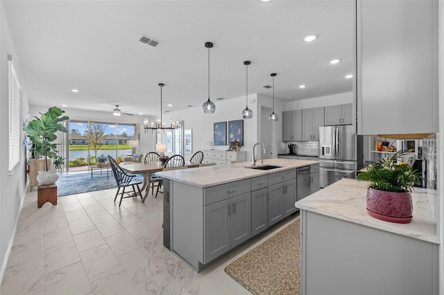 kitchen featuring a center island with sink, hanging light fixtures, gray cabinetry, and sink