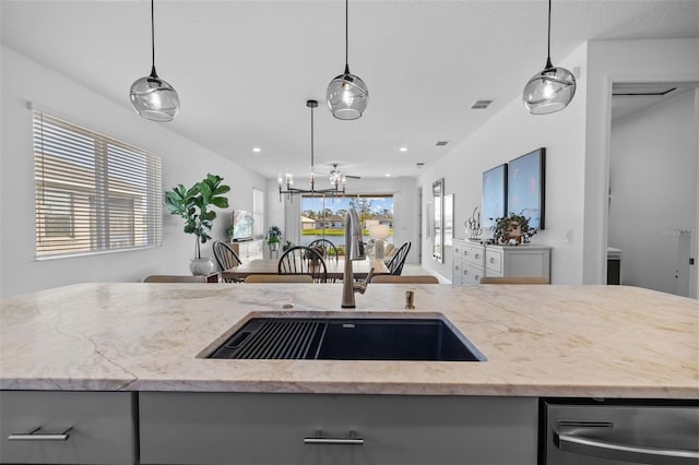 kitchen with sink, hanging light fixtures, a center island with sink, and an inviting chandelier