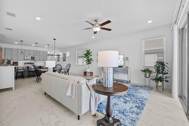 living room featuring ceiling fan with notable chandelier