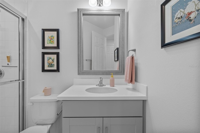 bathroom with vanity, toilet, and a shower with door