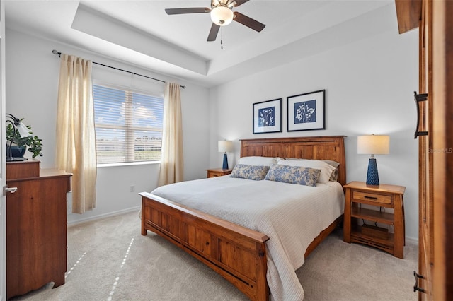 bedroom with a tray ceiling, ceiling fan, and light colored carpet