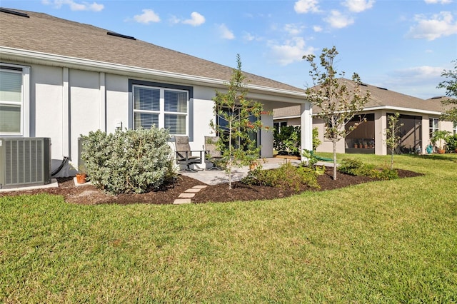 rear view of property featuring central AC unit, a patio area, and a lawn