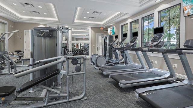 workout area with a raised ceiling and crown molding