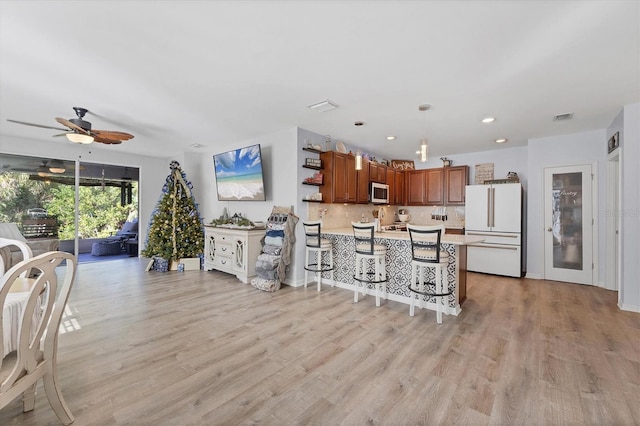 kitchen with ceiling fan, light hardwood / wood-style flooring, pendant lighting, and white refrigerator