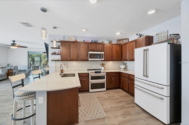 kitchen with white appliances, sink, hanging light fixtures, a kitchen bar, and kitchen peninsula