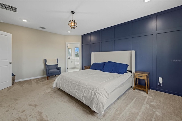 bedroom featuring ensuite bathroom and light colored carpet