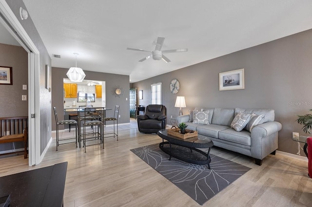 living room with ceiling fan and light hardwood / wood-style flooring