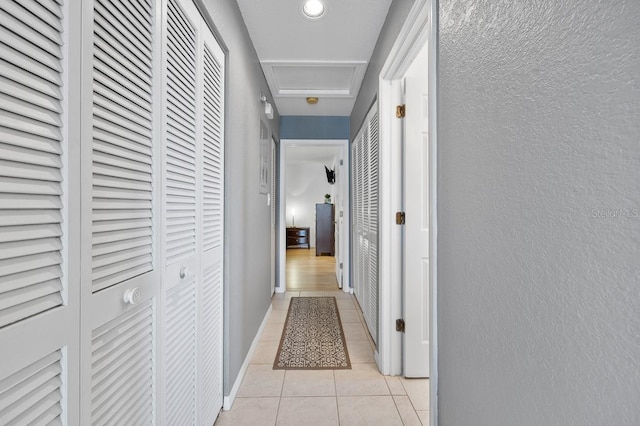 208 Lewis Cir Unit 4A, Punta Gorda, FL 33950 - corridor featuring attic access, light tile patterned flooring, a textured wall, and baseboards