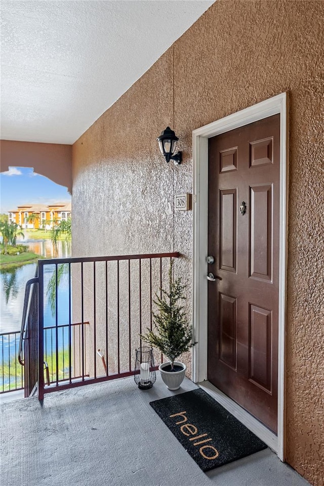 property entrance with a water view and a balcony