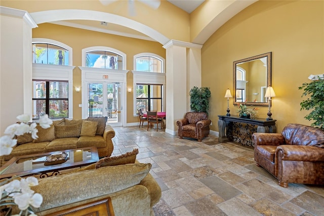 8377 38th Street Cir E Unit 308, Sarasota, FL 34243 - living room featuring arched walkways, a towering ceiling, stone tile flooring, ornamental molding, and french doors