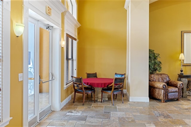 8377 38th Street Cir E Unit 308, Sarasota, FL 34243 - dining area featuring stone tile floors, a towering ceiling, and baseboards