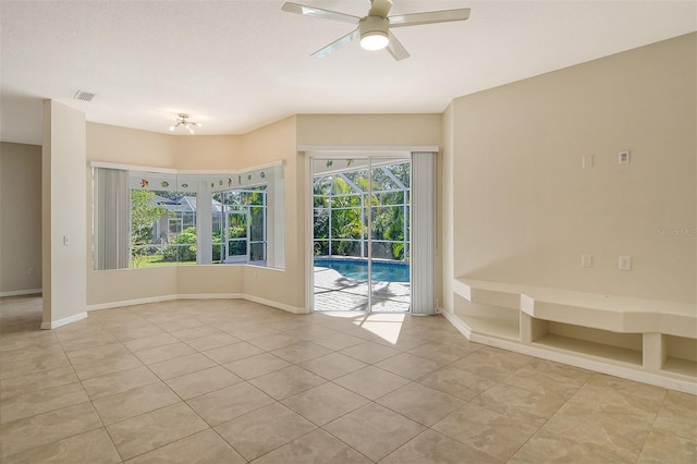 tiled empty room featuring plenty of natural light and ceiling fan