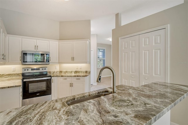 kitchen with white cabinets, light stone counters, sink, and stainless steel appliances