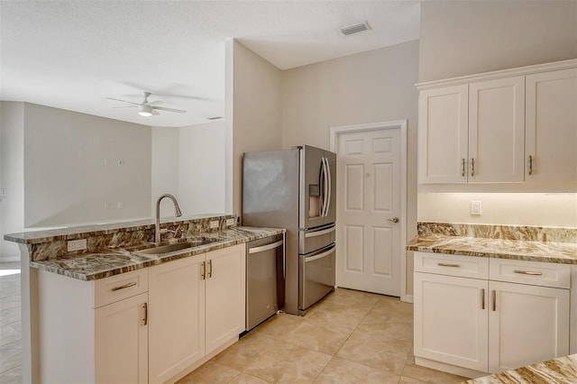 kitchen with light stone countertops, sink, ceiling fan, stainless steel appliances, and a textured ceiling