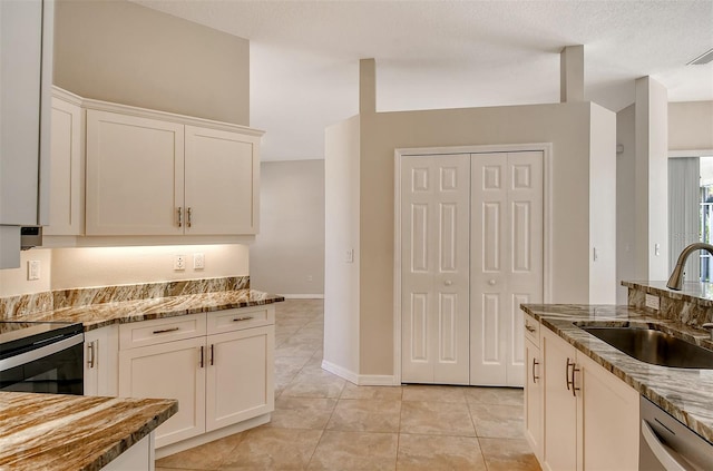 kitchen with stainless steel appliances, light stone counters, white cabinetry, and sink