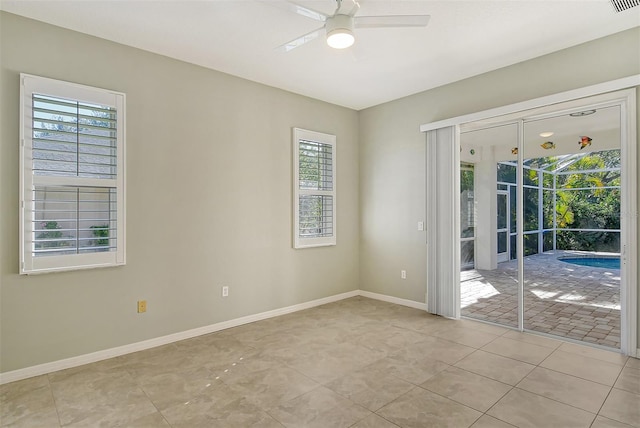 empty room with ceiling fan and light tile patterned floors