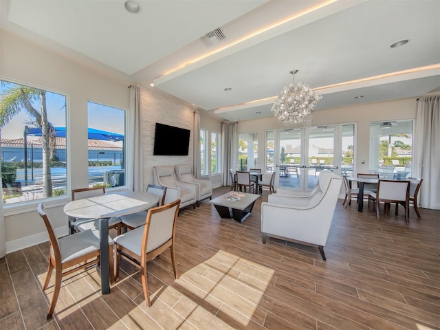 living room featuring french doors, a water view, a healthy amount of sunlight, and wood-type flooring