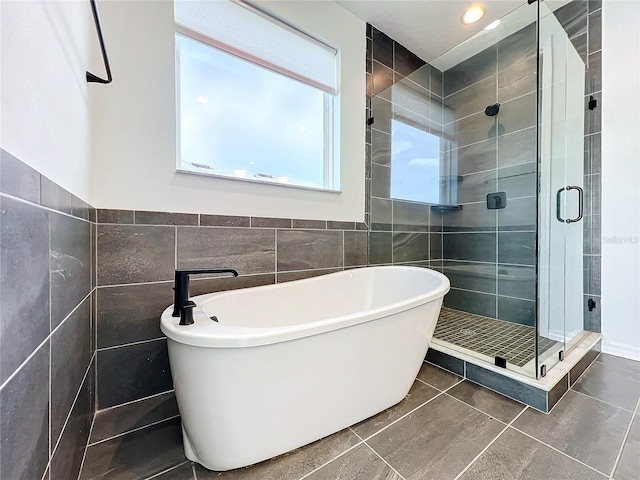 bathroom with tile walls, separate shower and tub, and tile patterned flooring