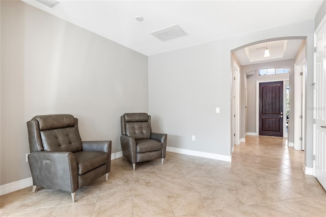 living area with a raised ceiling and light tile patterned floors